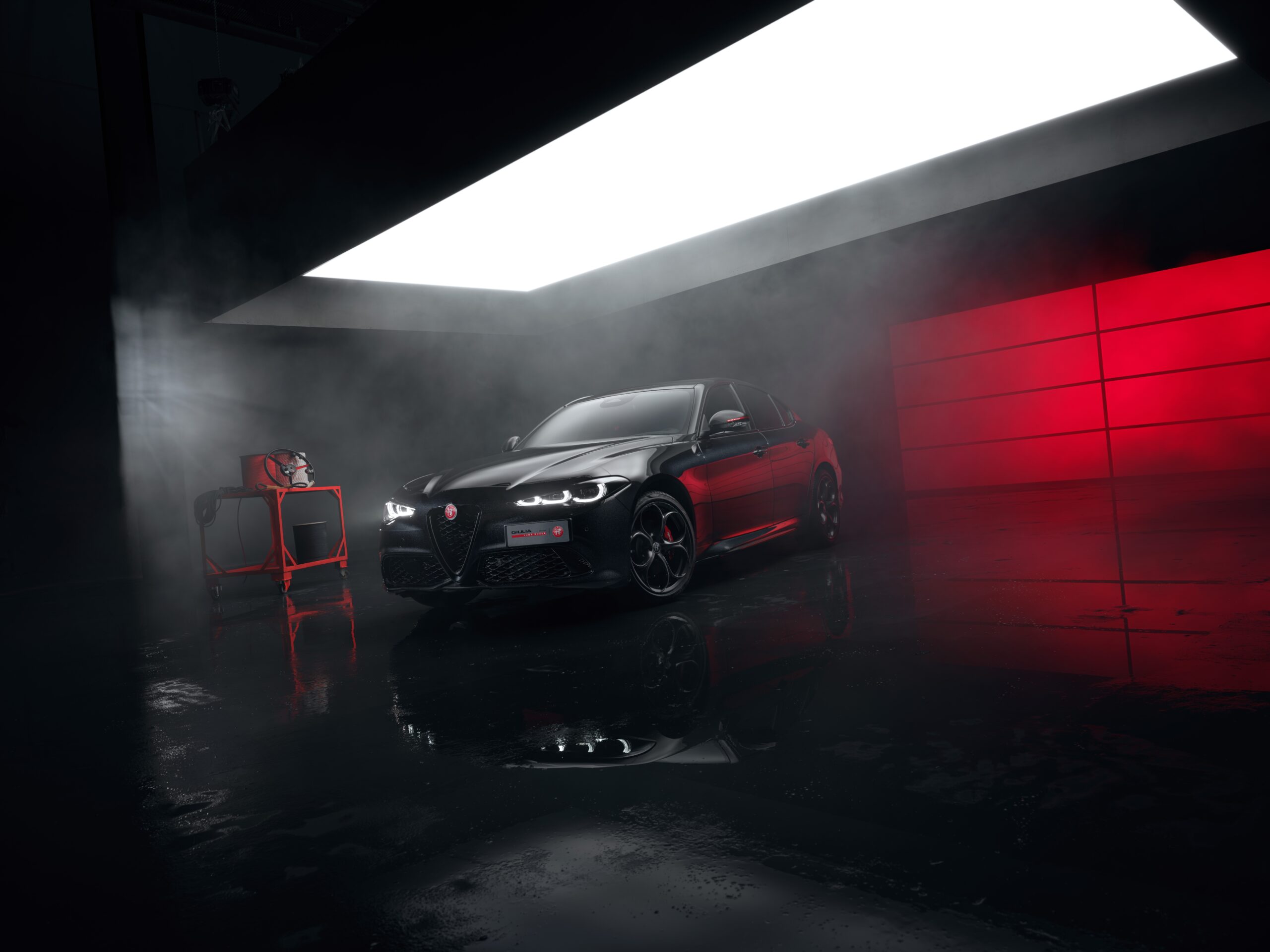 Alfa Romeo Giulia Luna Rossa nera con pinze freno rosse, nello studio con luce rossa
